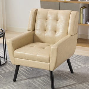 A beige tufted vegan-leather armchair features an elegant design with button detailing, a high back, angled arms, and sturdy black wooden legs.