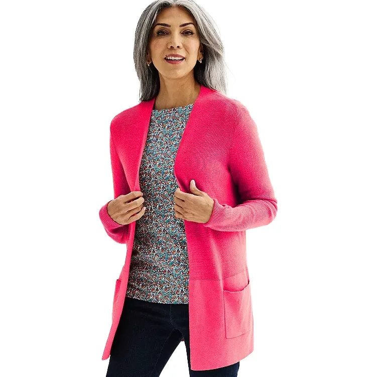 Bright pink, open-front cardigan with long sleeves and patch pockets, featuring a ribbed texture. Worn over a patterned top, paired with dark pants.