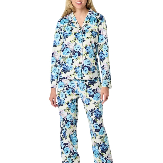 A woman wearing floral-patterned pajamas with a mix of blue, white, and green colors. The set includes a long-sleeve top and matching pants.