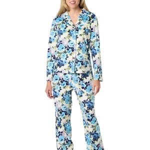 A woman wearing floral-patterned pajamas with a mix of blue, white, and green colors. The set includes a long-sleeve top and matching pants.