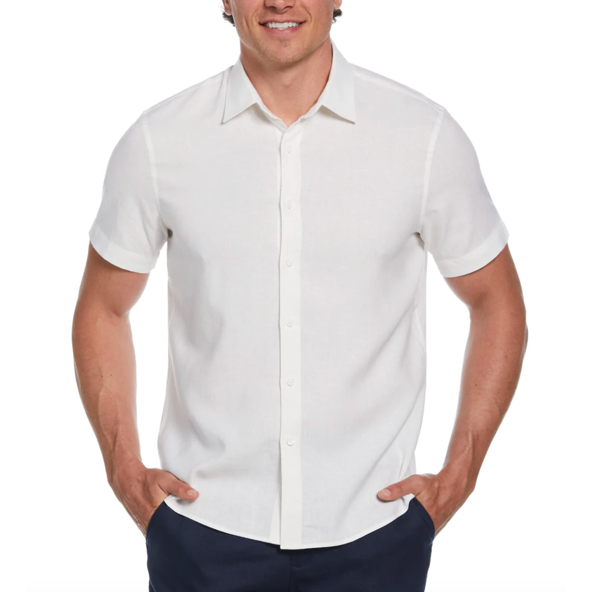 A man is wearing a short-sleeve, white button-up shirt with a collar, paired with dark trousers.