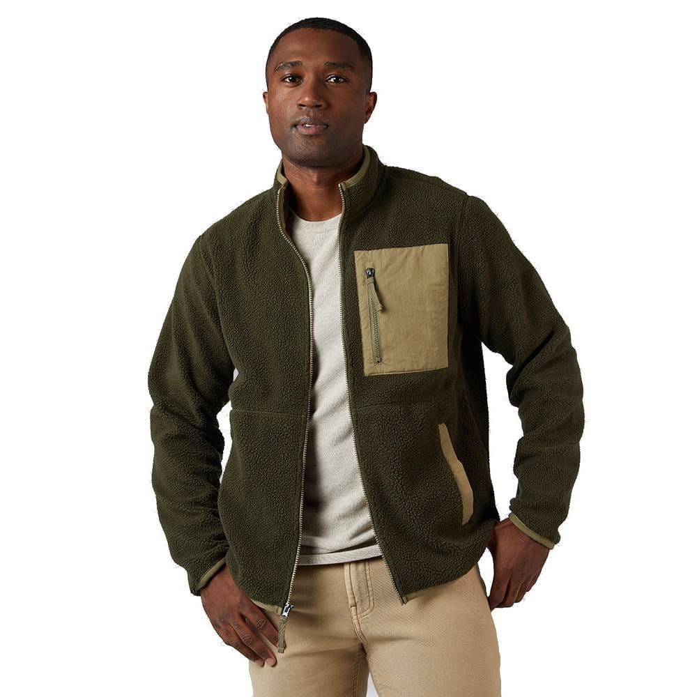 A man is wearing an olive green fleece jacket with a tan chest pocket and a zip closure, paired with a light-colored T-shirt and beige pants.