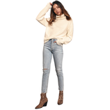 A woman is wearing a cream turtleneck sweater, light blue ripped jeans, and leopard print ankle boots.