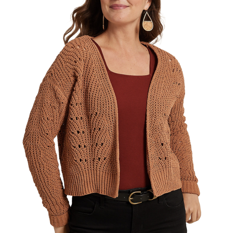 A woman wears a brown knitted cardigan over a maroon top, paired with black jeans and a gold buckle belt, accessorized with teardrop-shaped earrings.