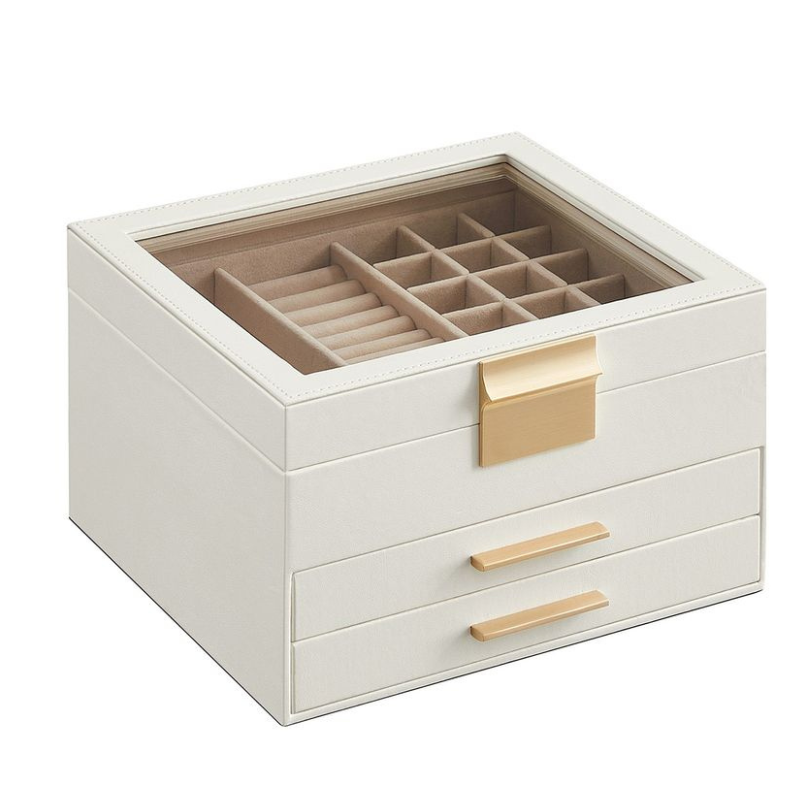 A cream-colored jewelry box with a glass top, featuring compartments for rings and accessories, accented with gold handles and a clasp.