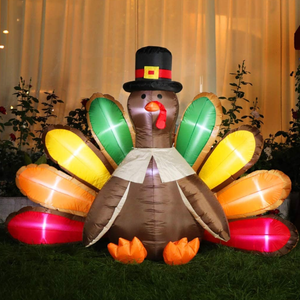 Inflatable turkey decoration with colorful tail feathers and a pilgrim hat, placed outside on grass, illuminated from within.