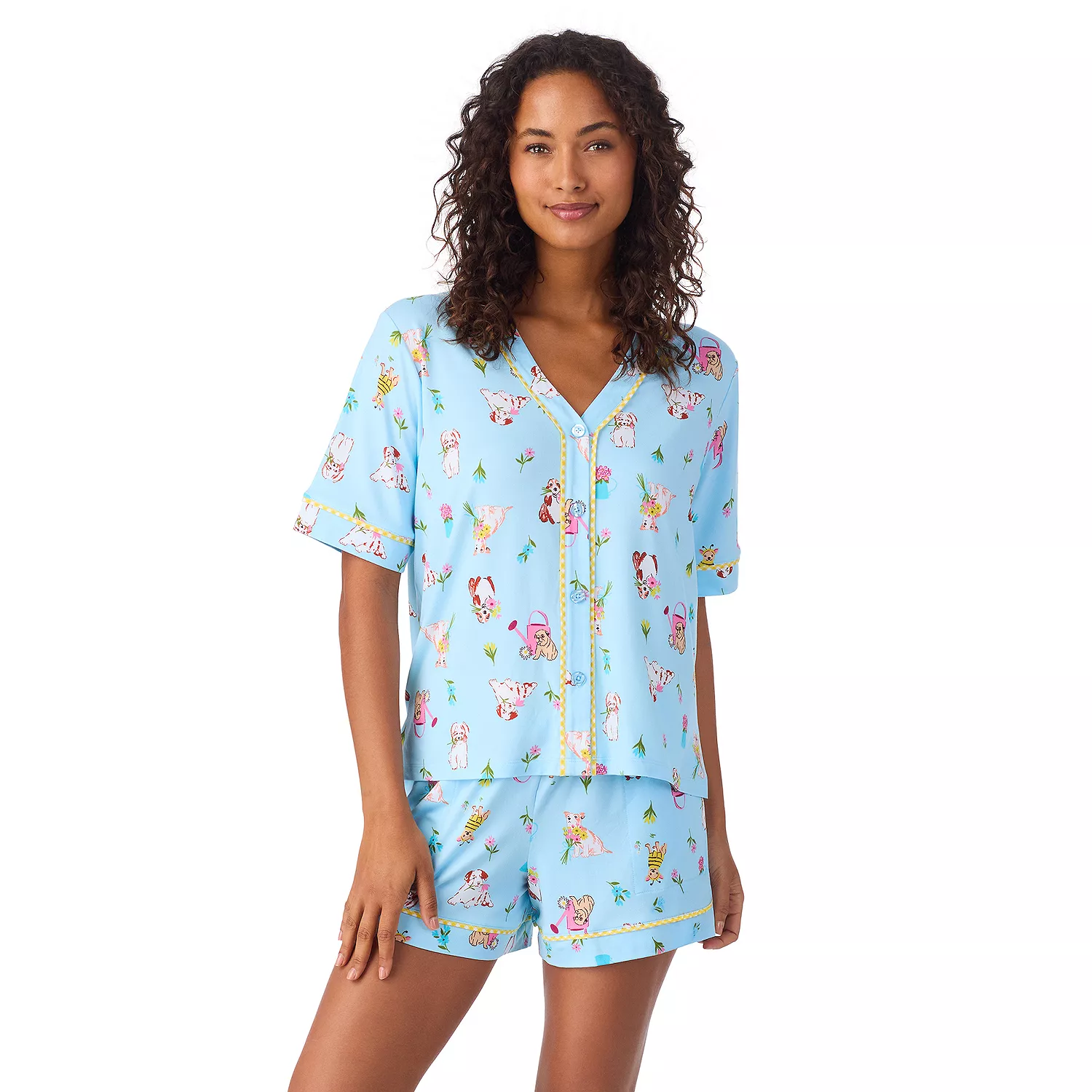 A woman is wearing a light blue pajama set featuring short sleeves and shorts, covered in playful animal prints and small decorative elements.