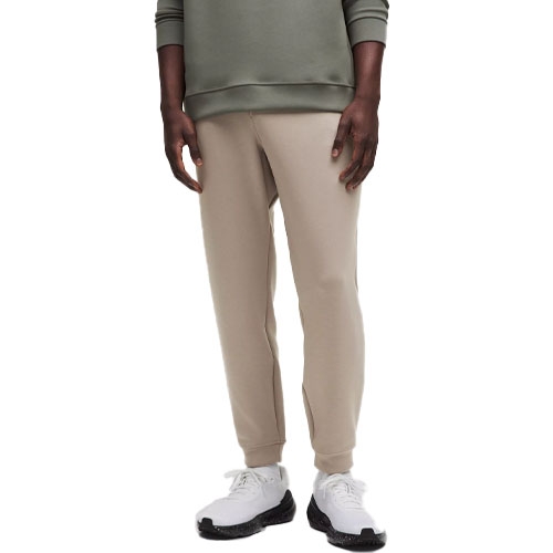 A person wearing beige jogger pants paired with a green top and white sneakers with black soles.