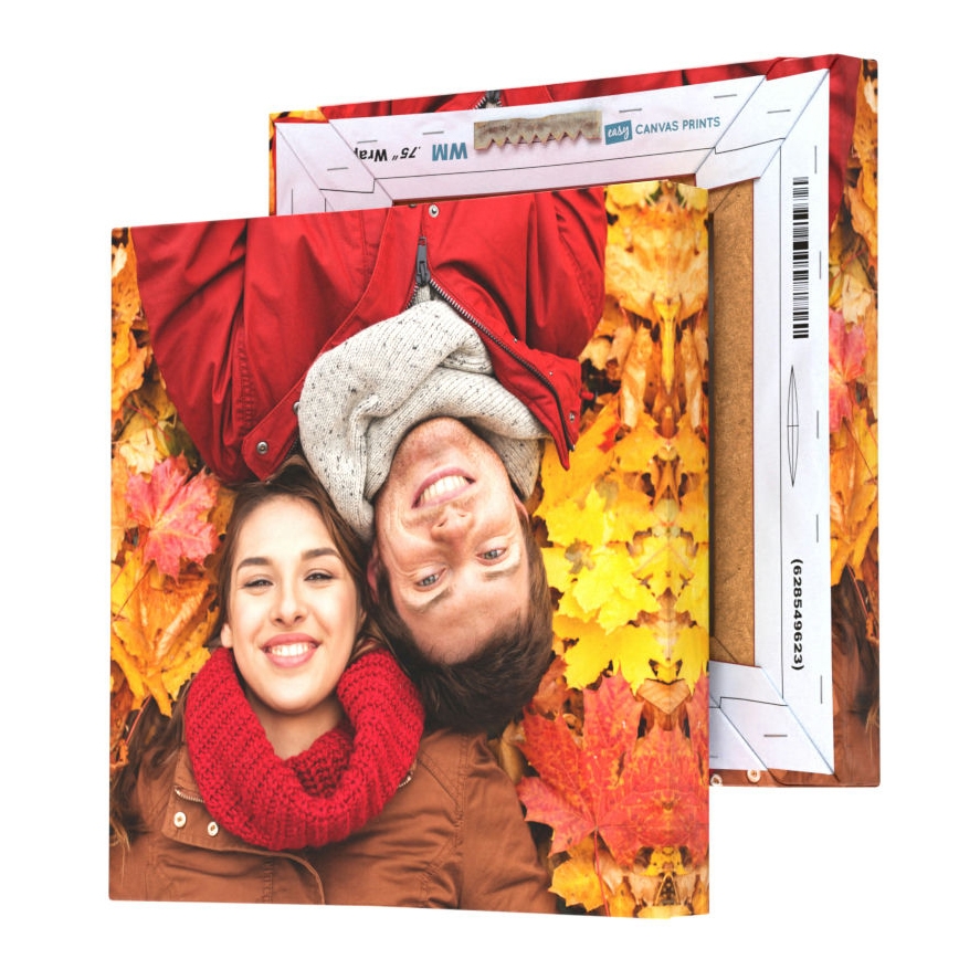 A canvas print showing a couple lying in autumn leaves, with the canvas wrapping extending around the sides of the wooden frame.