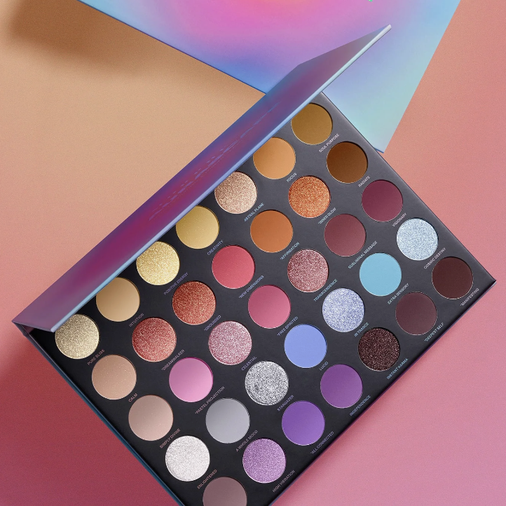 A colorful eyeshadow palette with a variety of shimmer and matte shades displayed open.