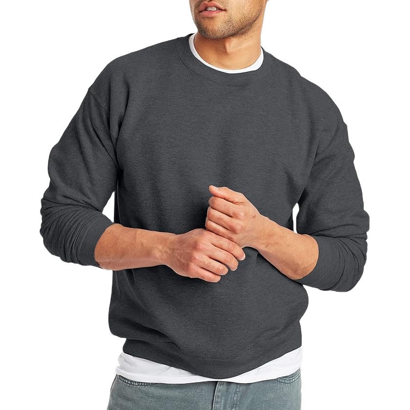 A man in a dark gray crewneck sweatshirt layered over a white t-shirt and paired with light gray pants.