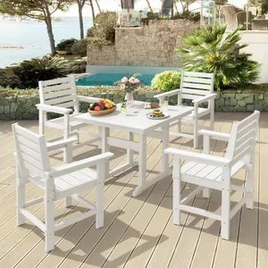 White outdoor dining set with four chairs and a table on a deck, featuring a fruit bowl, drinks, and flowers. The setting overlooks a swimming pool and scenic water view surrounded by greenery.