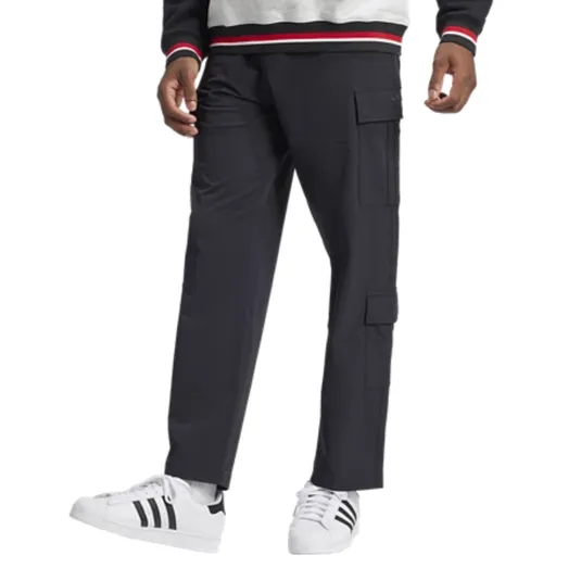 A person wearing black cargo pants with side pockets and white sneakers featuring black stripes, highlighted by a gray sweatshirt with red and white striped cuffs and waistband.