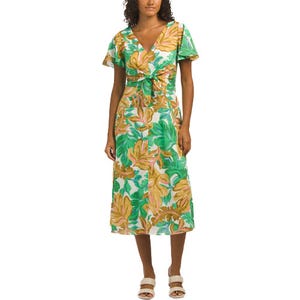 A knee-length, short-sleeve dress with a green and gold leafy print, featuring a V-neckline and a front knot detail. Paired with white sandals.