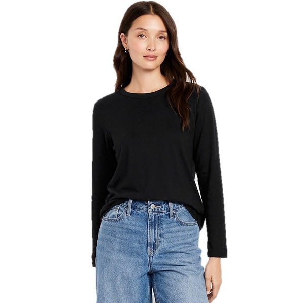 A woman is wearing a black long-sleeve shirt paired with high-waisted blue jeans.