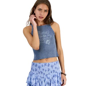 Woman wearing a sleeveless blue crop top with \“Born to be a cowgirl\“ text and a blue patterned tiered skirt.