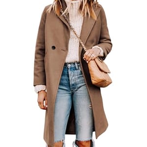 A woman wears a brown knee-length coat over a white knit sweater with ripped blue jeans, accessorized with a beige quilted handbag and sunglasses.