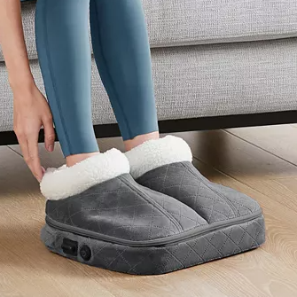 A pair of oversized, quilted gray slippers with plush white lining, featuring a side control button, designed to warm feet.