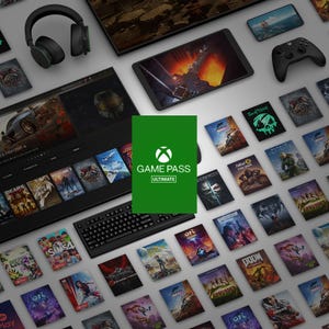 The photo shows electronic devices, like a tablet and headphones, surrounded by various video game covers, with an Xbox Game Pass Ultimate card featured centrally.
