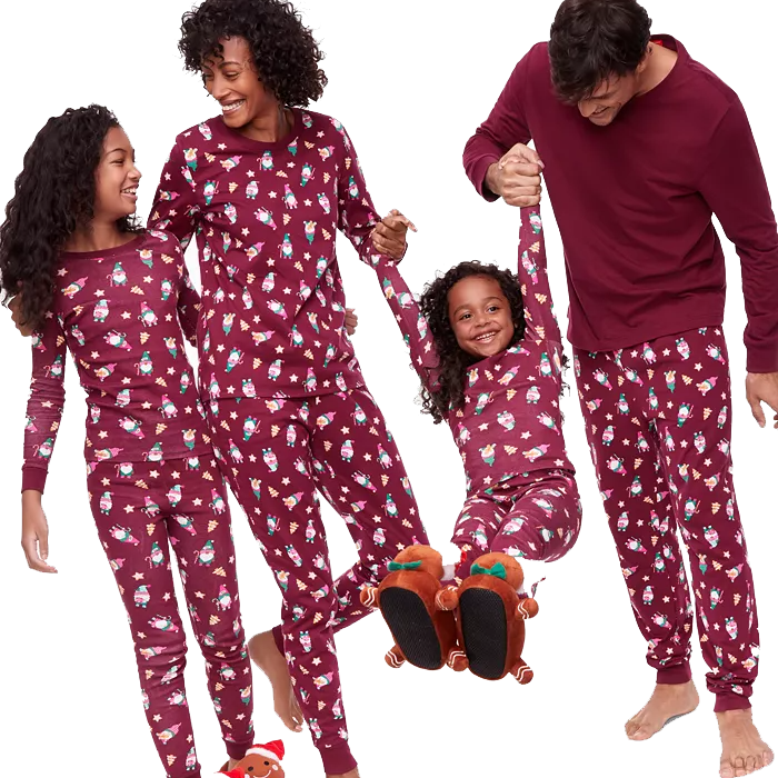 A family of four wearing matching maroon pajamas with festive prints, including reindeer slippers for one child and bundled feet for the others.