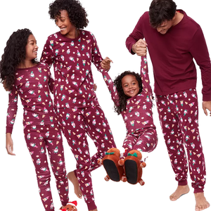 A family of four wearing matching maroon pajamas with festive prints, including reindeer slippers for one child and bundled feet for the others.
