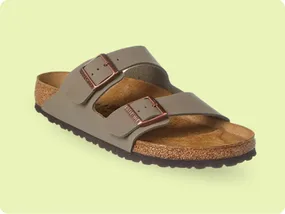 A sandal with two adjustable straps and buckles, featuring a cork footbed and a rubber sole, displayed on a light green background.