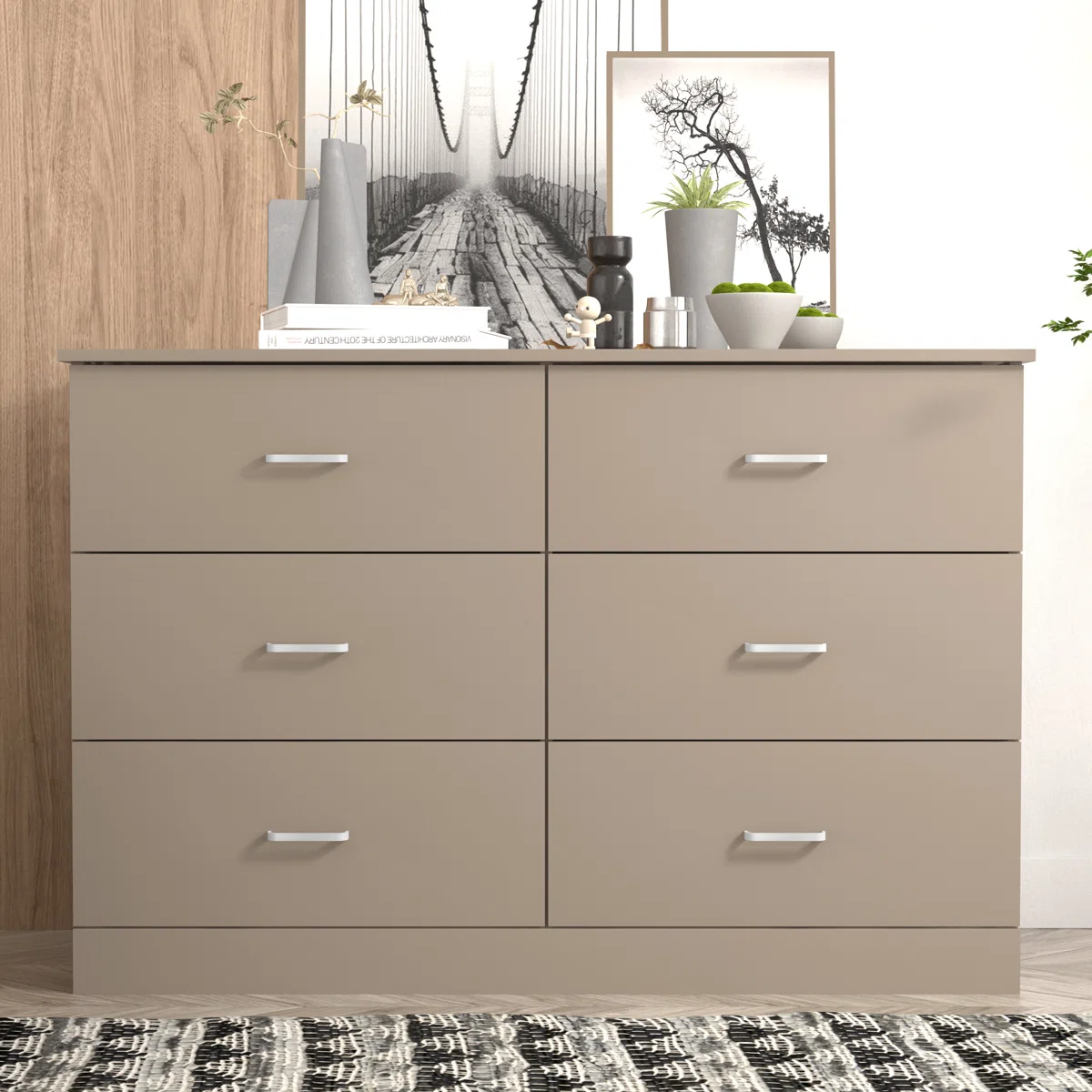 A six-drawer dresser in a neutral color is topped with books, decor items, plants, and framed artwork.