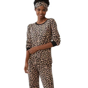 A woman is wearing a matching leopard print pajama set with long sleeves and pants, accompanied by a headband in the same pattern.