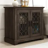 A dark wood cabinet with decorative glass-paneled doors, featuring a geometric pattern and black handles, is shown. It contains shelves holding books and other items.