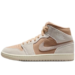 A mid-top sneaker in beige and tan tones with a suede texture, featuring a prominent swoosh and embossed details on the ankle.