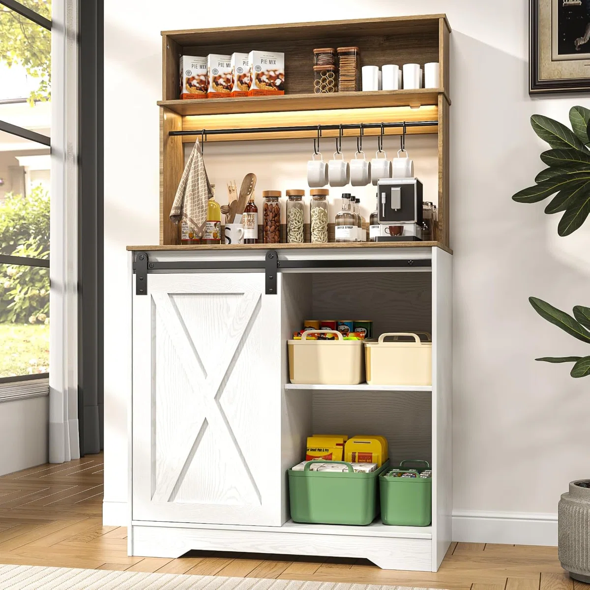 A freestanding kitchen storage cabinet with a farmhouse-style sliding barn door, open shelving for dry goods, a coffee maker, and wall hooks for cups. It includes bins for organized storage.
