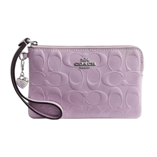 A lavender Coach wristlet features an embossed pattern with the Coach logo in metal. It includes a detachable wrist strap and a small heart charm.