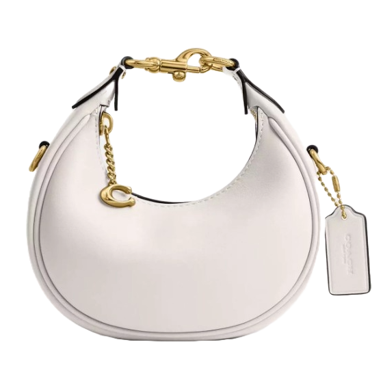 A round, white handbag with gold hardware, featuring a decorative \“C\“ charm and a tag with embossed lettering.