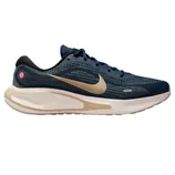 A navy and beige Nike running shoe with a textured mesh upper, featuring a prominent swoosh, cushioned sole, and small pink accent.