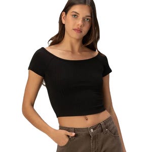 A black, short-sleeve boat-neck tee with a fitted, cropped design. Styled with casual brown pants.