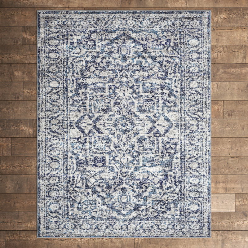 A rectangular area rug with a blue and white intricate floral and geometric pattern on a wooden floor.