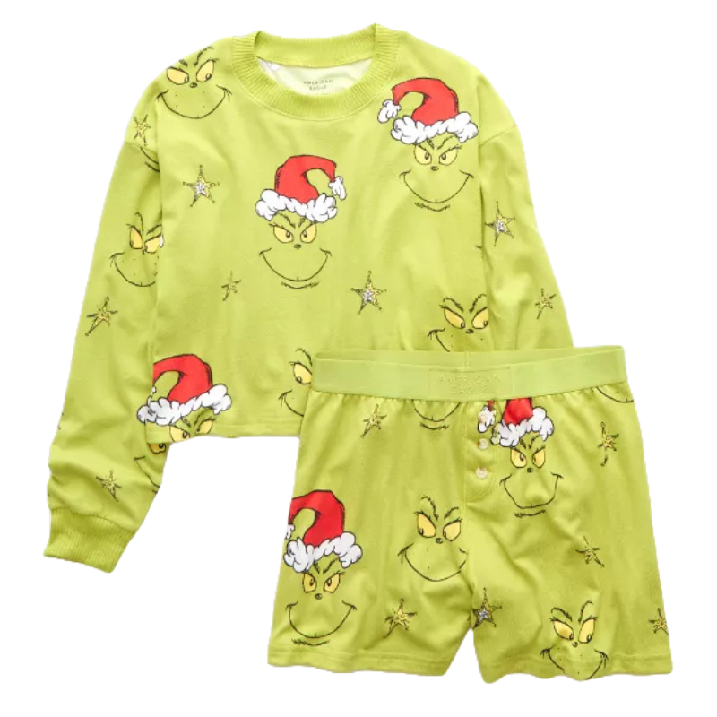 A green 2-piece American Eagle plush pajama set featuring a long-sleeve top and shorts, adorned with the Grinch's face wearing a Santa hat and star accents.
