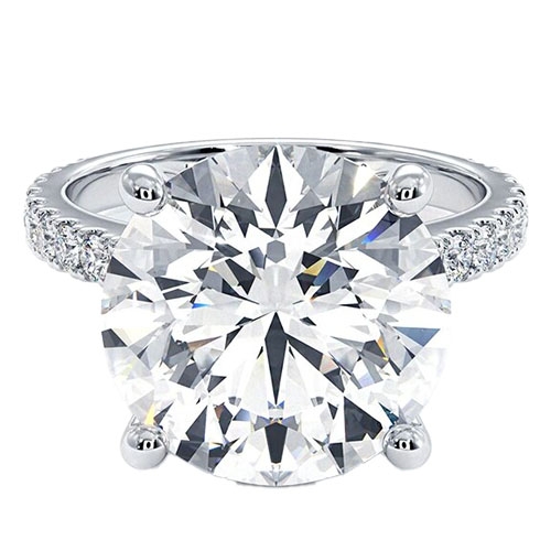 A round-cut diamond ring with a large center stone set in a four-prong setting, featuring a pavé diamond band on a silver or white gold metal.