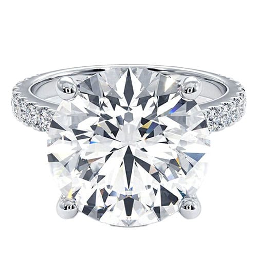 A round-cut diamond ring with a large center stone set in a four-prong setting, featuring a pavé diamond band on a silver or white gold metal.
