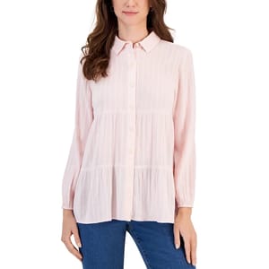 A woman is wearing a pink, striped, button-up blouse with a collar and long sleeves, paired with blue jeans.