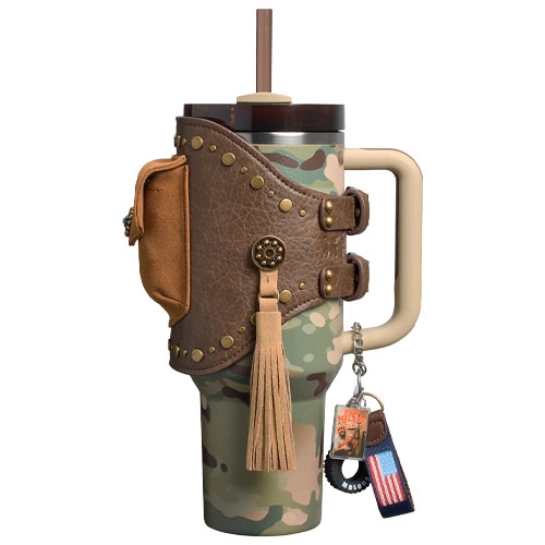A camouflage tumbler with a faux leather holster and tassel, featuring a handle and a straw. It includes decorative studs and a keychain with an American flag design.