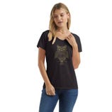 A woman is wearing a black T-shirt with a gold owl design on the front, paired with blue jeans and a colorful bead necklace.