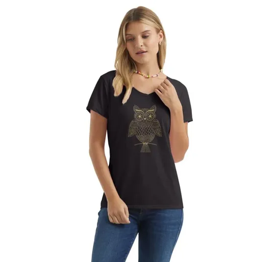 A woman is wearing a black T-shirt with a gold owl design on the front, paired with blue jeans and a colorful bead necklace.