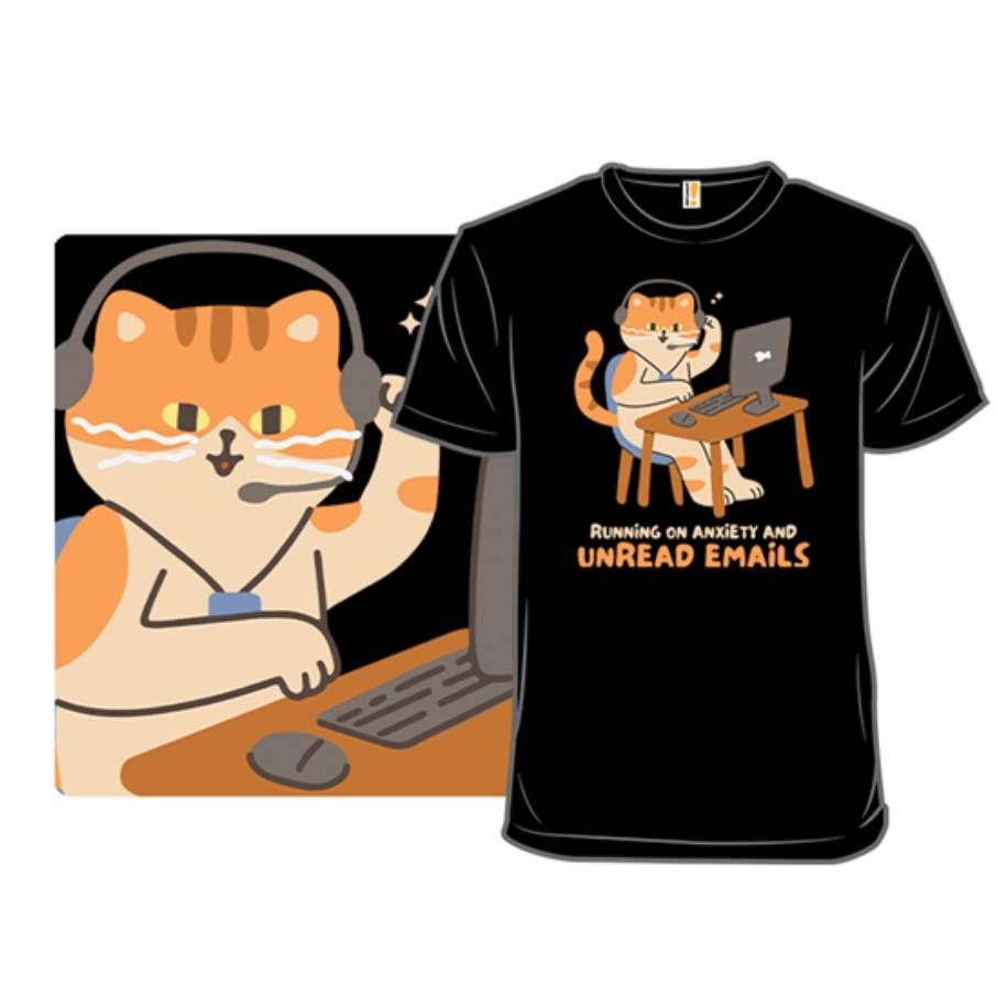 A black T-shirt features an illustration of a cat wearing headphones and working on a laptop, with the text \“Running on anxiety and unread emails.\“