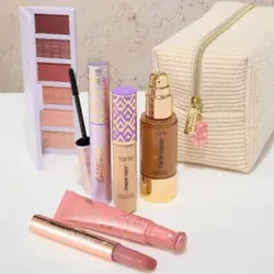 A set of makeup items including an eyeshadow palette, mascara, concealer, foundation, lipstick, blush, and a cosmetic bag. The products feature pastel and gold packaging.