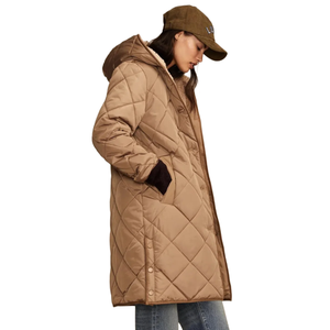 A person is wearing a tan quilted coat with a hood, paired with a brown baseball cap and blue jeans. The coat features a diamond pattern and snap closures.