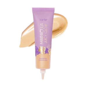 Tarte Maracuja Juicy Glow foundation in a purple tube with golden and lavender floral design, displayed with a swipe of foundation showcasing its creamy texture.
