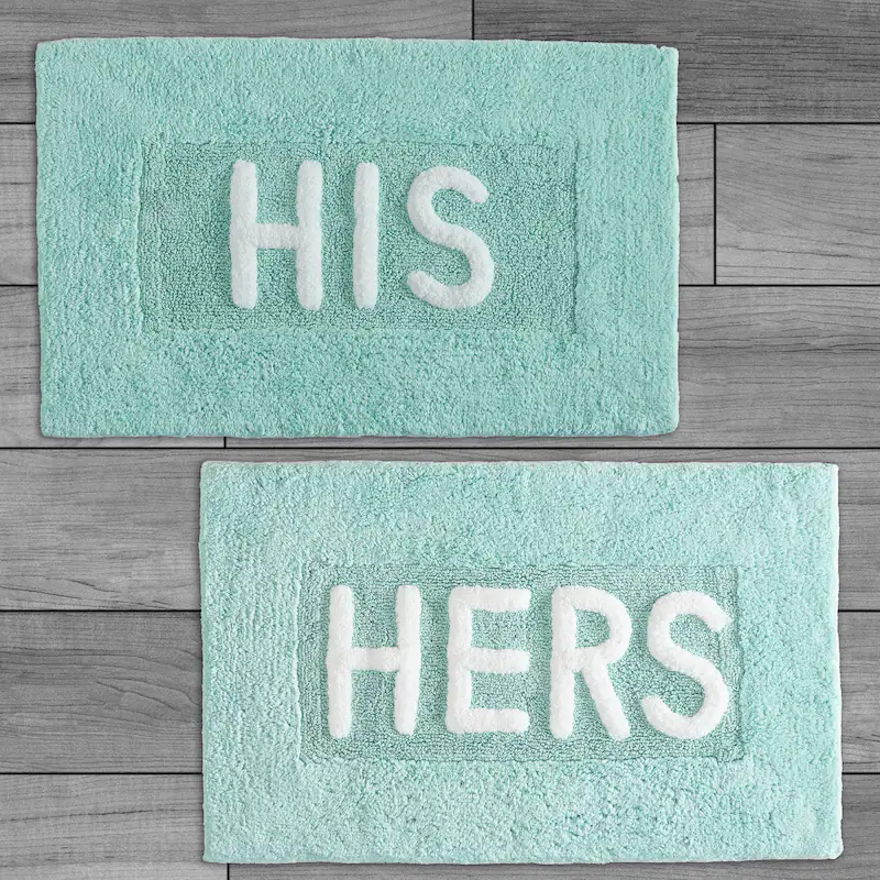 Two light blue bath mats with white text: one reads \“HIS\“ and the other \“HERS.\“
