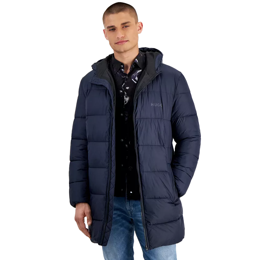 A navy hooded puffer parka with a quilted design, featuring the \“HUGO\“ logo on the chest. It has a front zipper closure and two side pockets, worn over a patterned shirt and jeans.