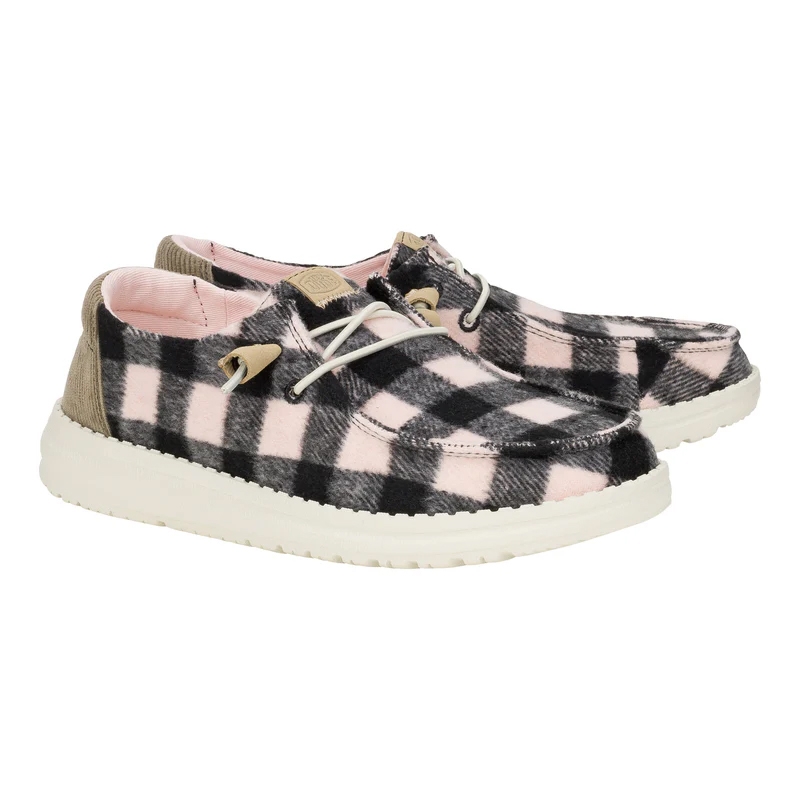 Hey Dude Women's Buffalo Plaid Shoes feature a pink and black plaid pattern with white soles and beige accents. They have a casual, slip-on design with white laces, and are lined with a soft pink interior.